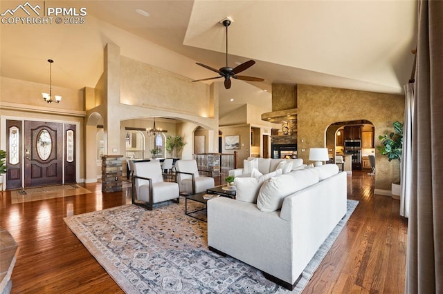 living room featuring arched walkways, a chandelier, a ceiling fan, high vaulted ceiling, and wood finished floors