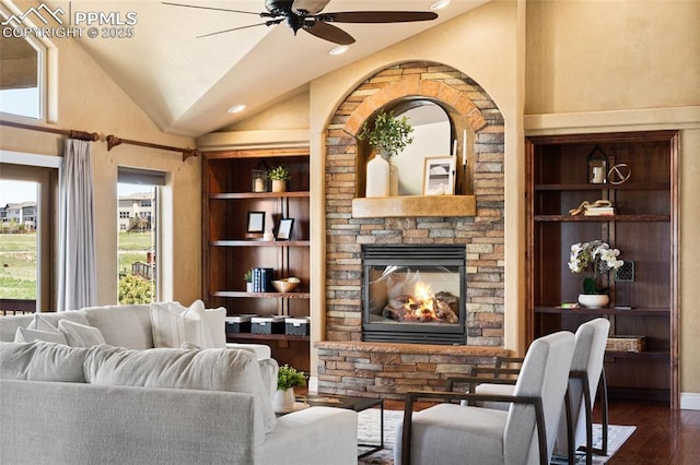 living room featuring ceiling fan, dark wood-type flooring, a fireplace, built in shelves, and lofted ceiling