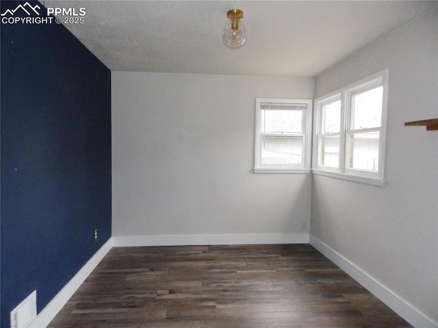empty room featuring visible vents, wood finished floors, and baseboards