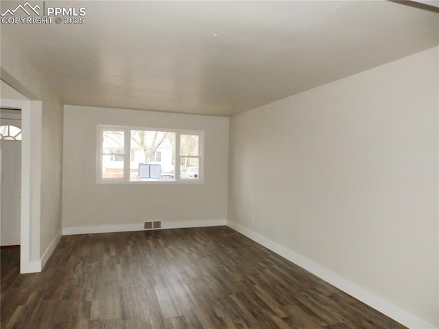 unfurnished room with baseboards, dark wood-type flooring, and visible vents