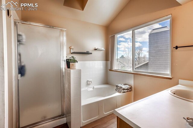 full bath featuring a garden tub, a shower stall, vaulted ceiling, wood finished floors, and a sink