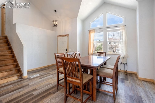dining space featuring stairs, high vaulted ceiling, baseboards, and light wood-style floors