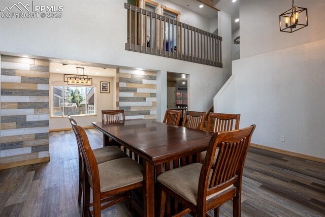 dining room with an inviting chandelier, baseboards, a high ceiling, and wood finished floors