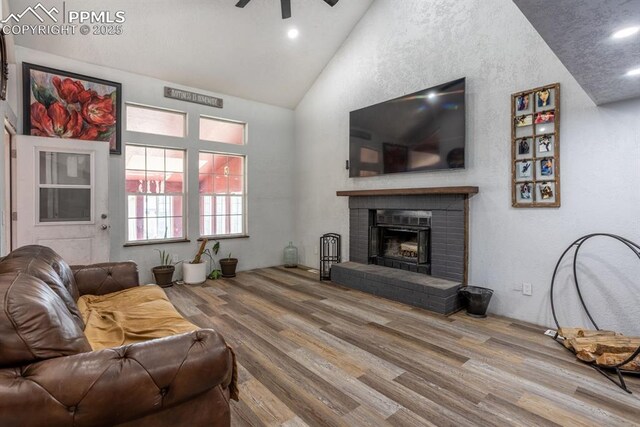 living room with ceiling fan, a fireplace, high vaulted ceiling, recessed lighting, and wood finished floors
