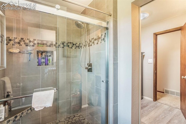 full bathroom with a shower stall, visible vents, and wood finished floors