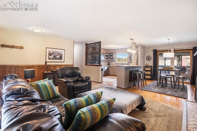 living room featuring wooden walls, light wood-type flooring, and a wainscoted wall
