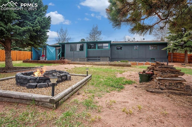 rear view of property with a fire pit and fence