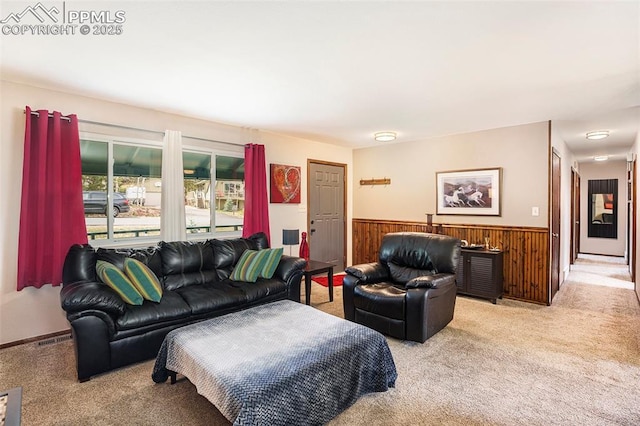 living area with visible vents, a wainscoted wall, light colored carpet, and wood walls