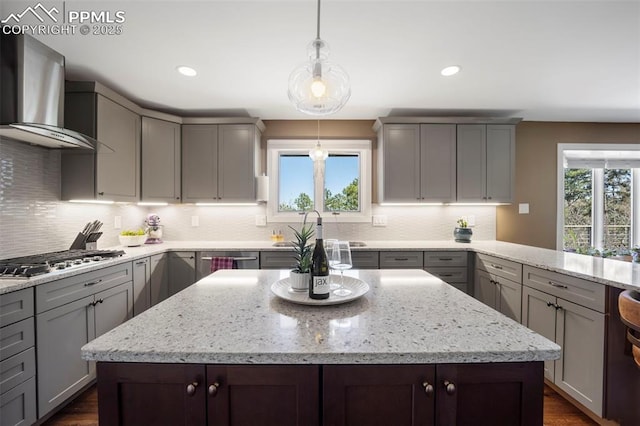 kitchen featuring appliances with stainless steel finishes, decorative backsplash, gray cabinets, and wall chimney exhaust hood