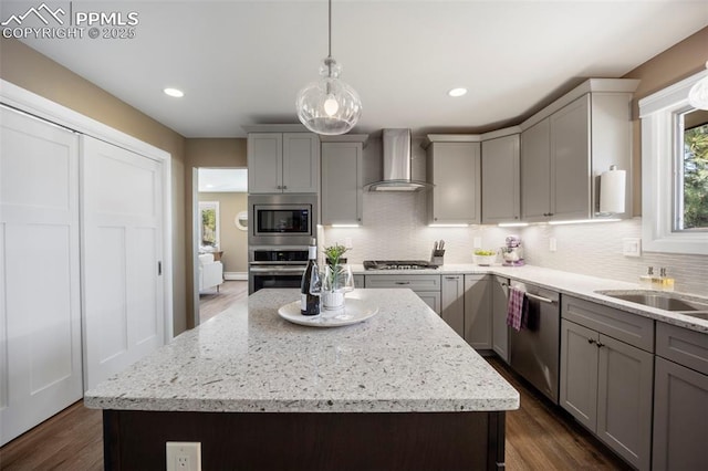 kitchen with wall chimney range hood, gray cabinetry, stainless steel appliances, and tasteful backsplash