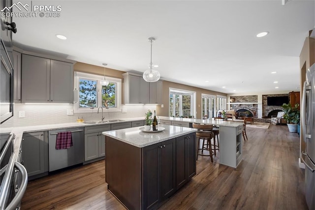 kitchen with gray cabinets, stainless steel dishwasher, stove, a sink, and a peninsula