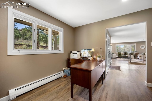 home office featuring baseboards, a baseboard heating unit, and wood finished floors