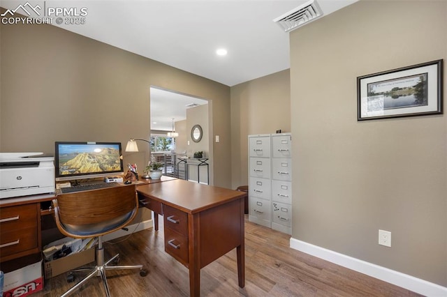 office space featuring baseboards, visible vents, and wood finished floors