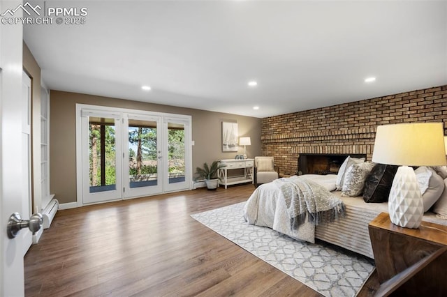 bedroom with brick wall, access to exterior, wood finished floors, and a baseboard radiator