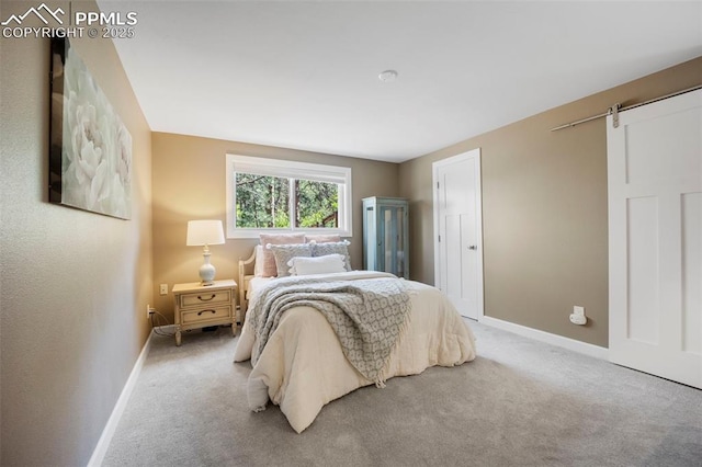 bedroom featuring baseboards, a barn door, and carpet