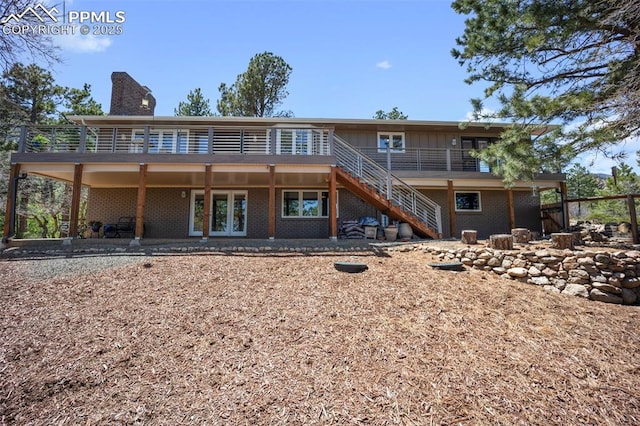 rear view of property featuring stairway, brick siding, and a chimney