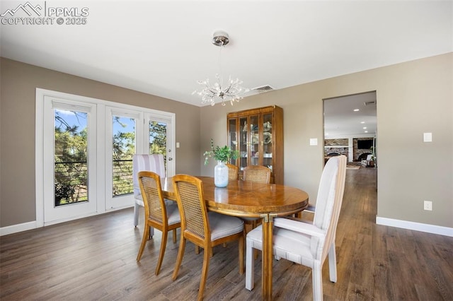 dining area featuring dark wood-style flooring, baseboards, an inviting chandelier, and visible vents