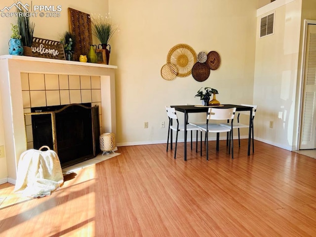 living room with visible vents, baseboards, wood finished floors, and a fireplace