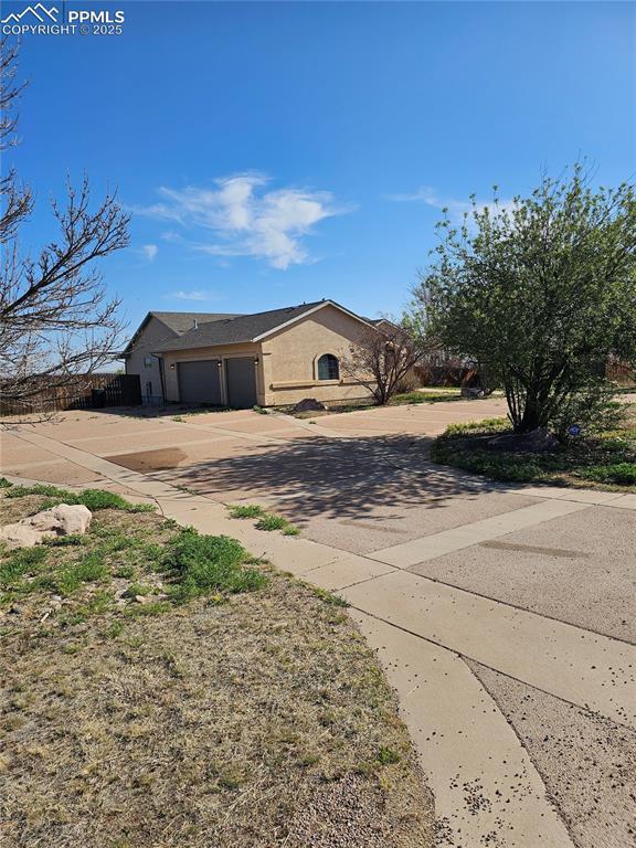 single story home featuring stucco siding, an attached garage, and concrete driveway