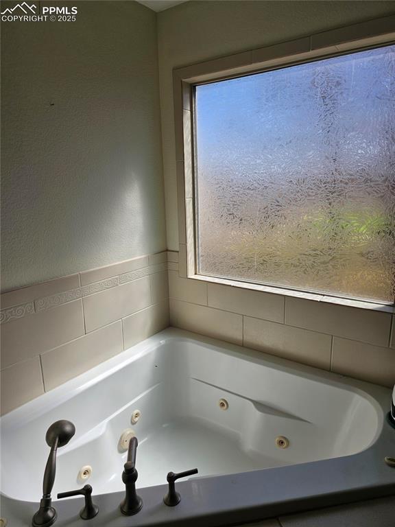 full bathroom featuring tile walls, a whirlpool tub, and a wealth of natural light