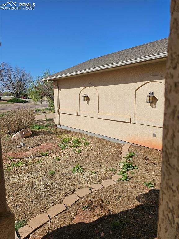 view of side of property featuring stucco siding and roof with shingles