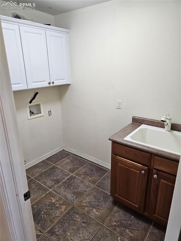 clothes washing area with baseboards, cabinet space, hookup for a washing machine, and a sink
