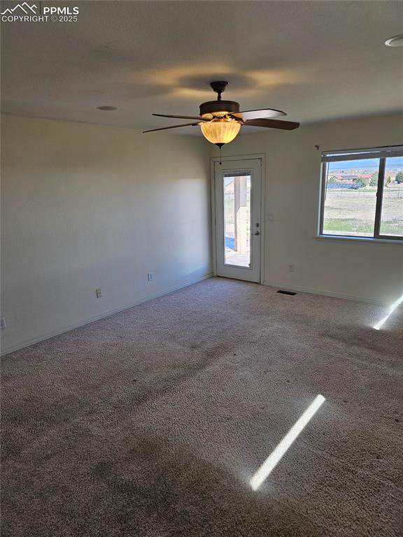 carpeted empty room featuring baseboards and a ceiling fan
