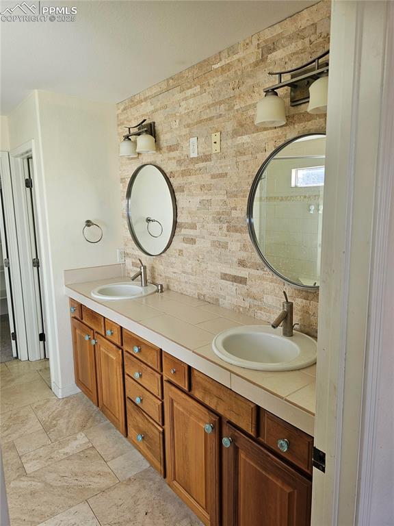bathroom with backsplash, double vanity, and a sink