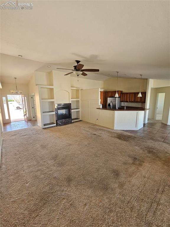unfurnished living room featuring lofted ceiling, a multi sided fireplace, carpet, and ceiling fan