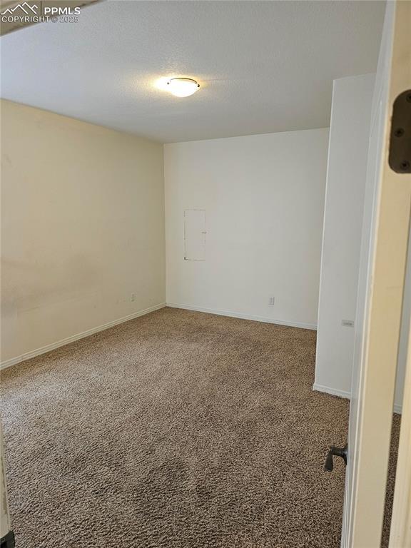 spare room featuring carpet floors and baseboards