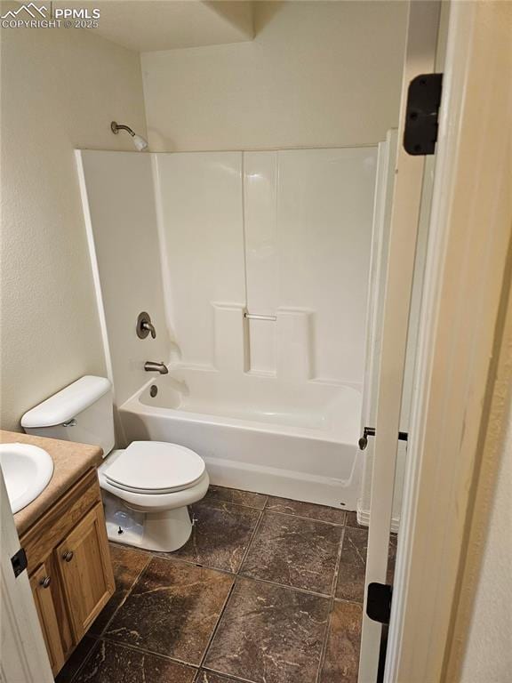 full bathroom with stone tile flooring, vanity,  shower combination, and toilet
