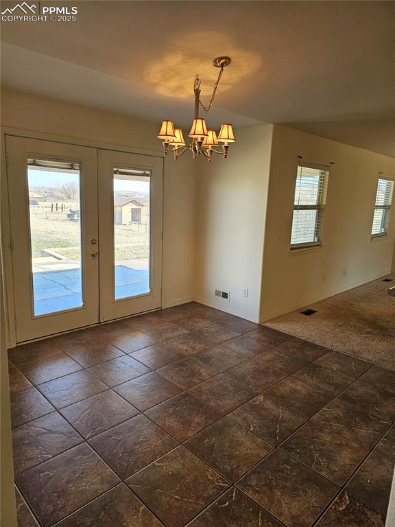 unfurnished dining area with baseboards, a notable chandelier, french doors, and visible vents