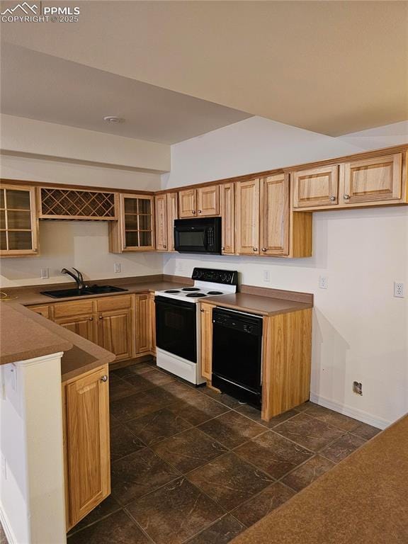 kitchen featuring a peninsula, a sink, baseboards, glass insert cabinets, and black appliances