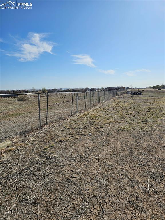 view of yard featuring fence and a rural view