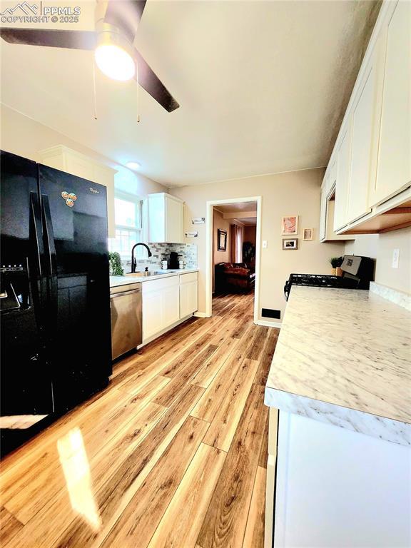 kitchen featuring white cabinets, light countertops, light wood-type flooring, appliances with stainless steel finishes, and ceiling fan