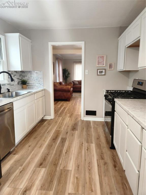 kitchen featuring light wood-style floors, a sink, white cabinetry, and appliances with stainless steel finishes