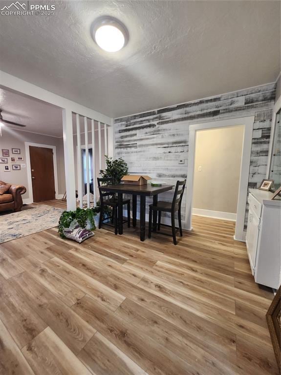 dining room with an accent wall, a textured ceiling, washer / dryer, light wood-style flooring, and baseboards