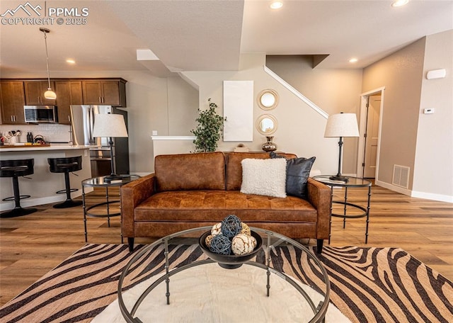 living room featuring recessed lighting, light wood-type flooring, and baseboards
