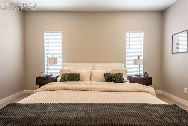 carpeted bedroom featuring baseboards and multiple windows