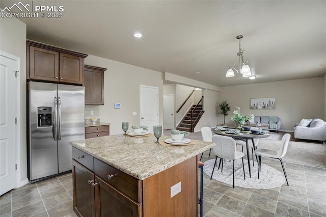 kitchen with stainless steel fridge with ice dispenser, a breakfast bar, a kitchen island, hanging light fixtures, and open floor plan
