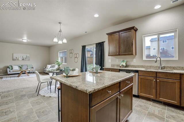 kitchen with stainless steel dishwasher, a sink, open floor plan, visible vents, and a kitchen island