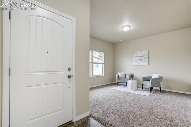 foyer entrance featuring dark colored carpet and baseboards