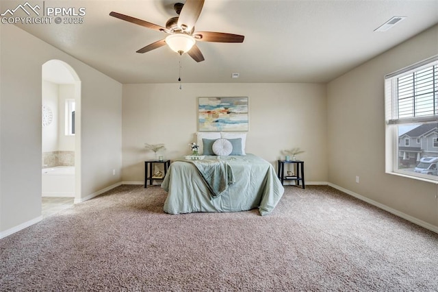 carpeted bedroom with visible vents, a ceiling fan, arched walkways, ensuite bath, and baseboards