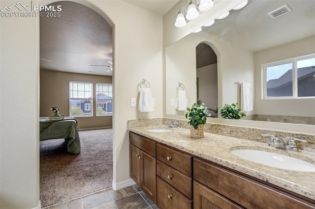 ensuite bathroom featuring a ceiling fan, a sink, visible vents, and double vanity