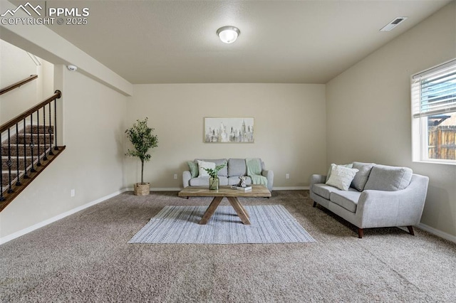 carpeted living area featuring baseboards, stairs, and visible vents