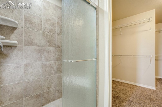 full bath featuring a shower stall and a walk in closet