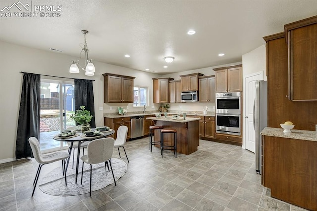 kitchen featuring a sink, a kitchen bar, appliances with stainless steel finishes, visible vents, and a kitchen island