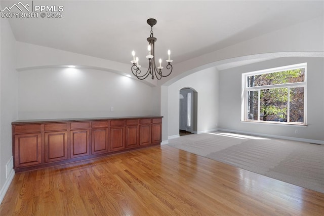 7436 Centennial Glen Dr, Colorado Springs, CO 80919 - interior space featuring light wood-style floors, arched walkways, a chandelier, baseboards, and visible vents
