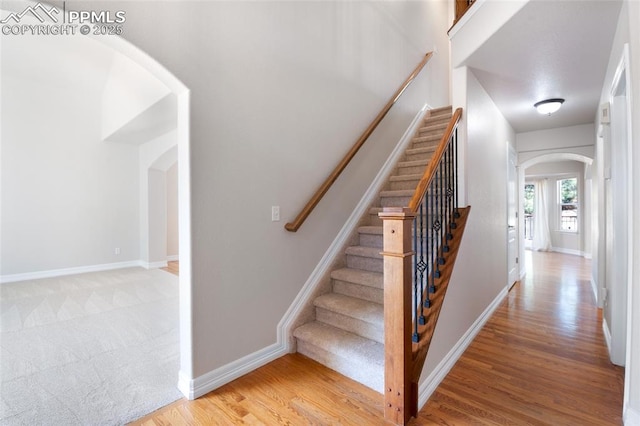7436 Centennial Glen Dr, Colorado Springs, CO 80919 - staircase featuring arched walkways, baseboards, and wood finished floors