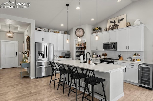 kitchen featuring tasteful backsplash, an island with sink, stainless steel appliances, a sink, and wine cooler
